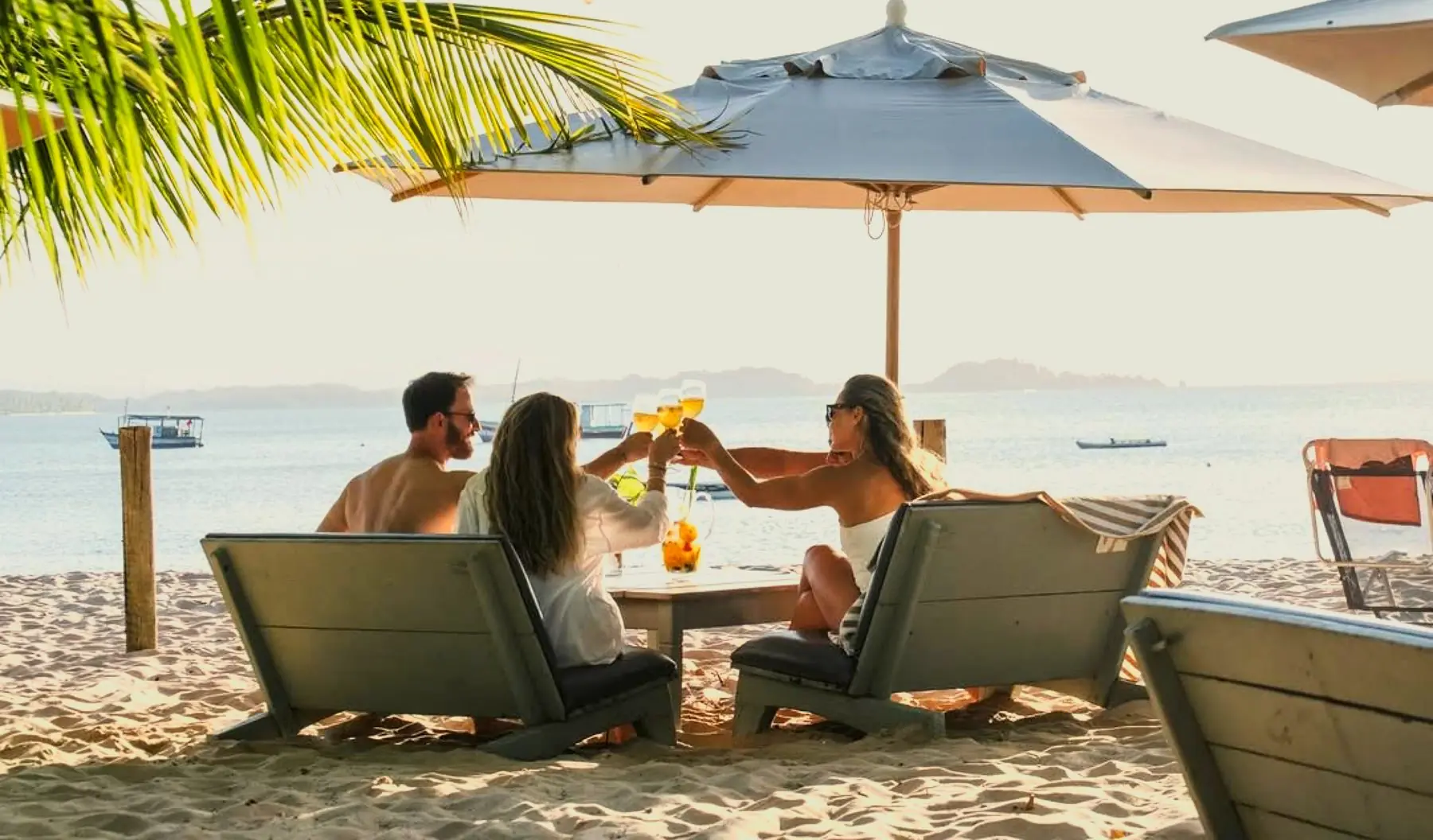 Mesa servida na areia sob guarda-sol, com o mar da Baía de Camamu ao fundo, no Obar em Barra Grande
