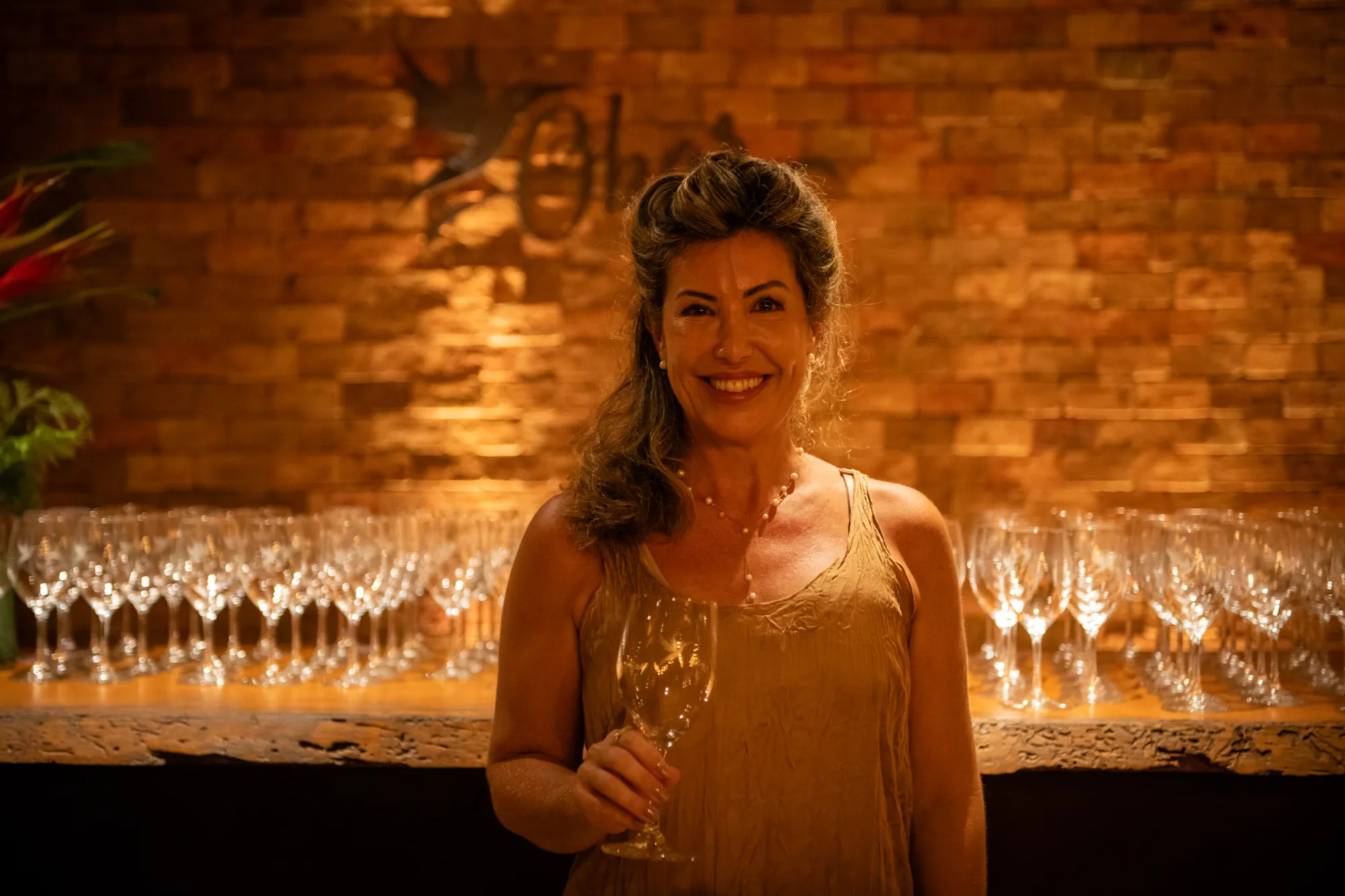 A sommelière Renata Formolo com uma taça, diante das taças de cristal do Wine Festival Obar