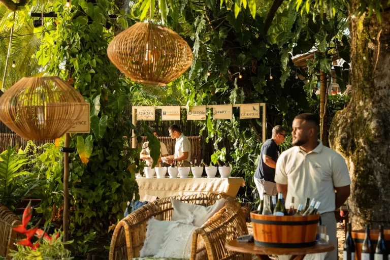 Estande de vinícola montado entre as plantas, com a equipe servindo