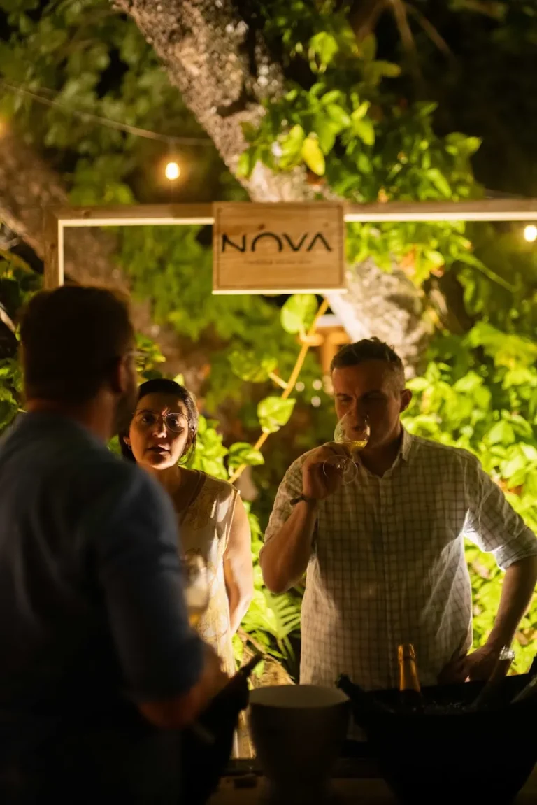 Convidados no estande da Nova Aliança, à noite, sob a placa da vinícola
