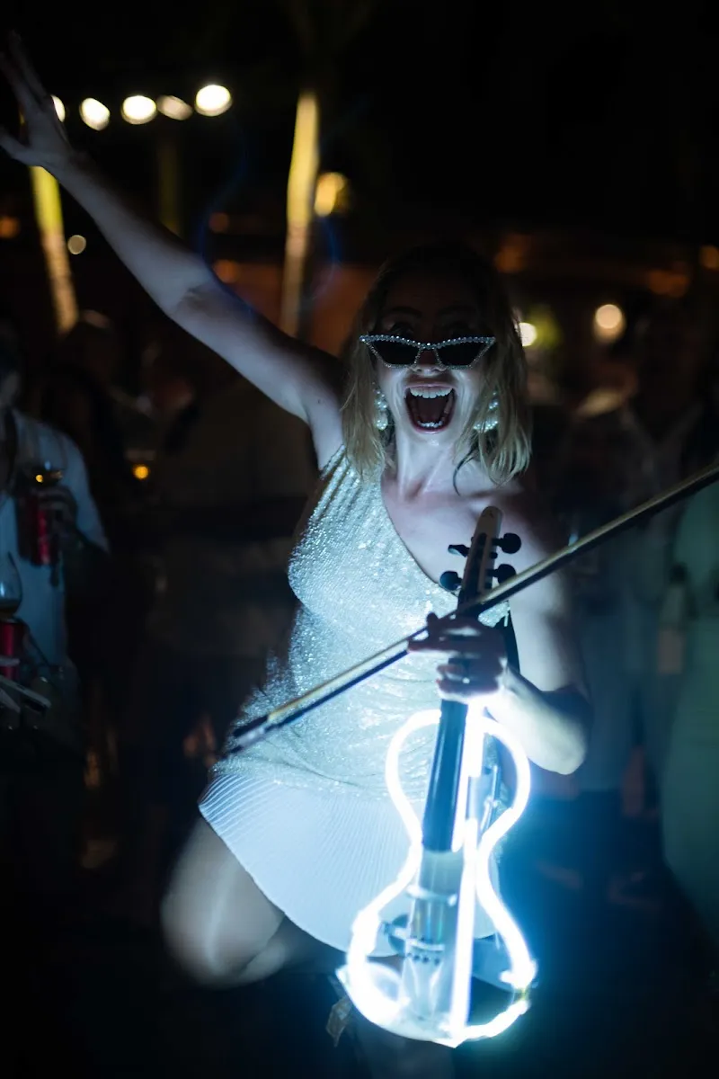 Karen Machado com o violino iluminado, sorrindo para o público